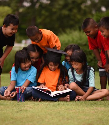 Group of children lying reading on grass field Group of children lying reading on grass field